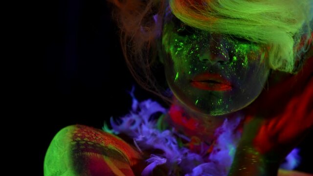 beautiful lady with bright makeup with fluorescent paints, ultraviolet light on face of model, orange, yellow and red colors