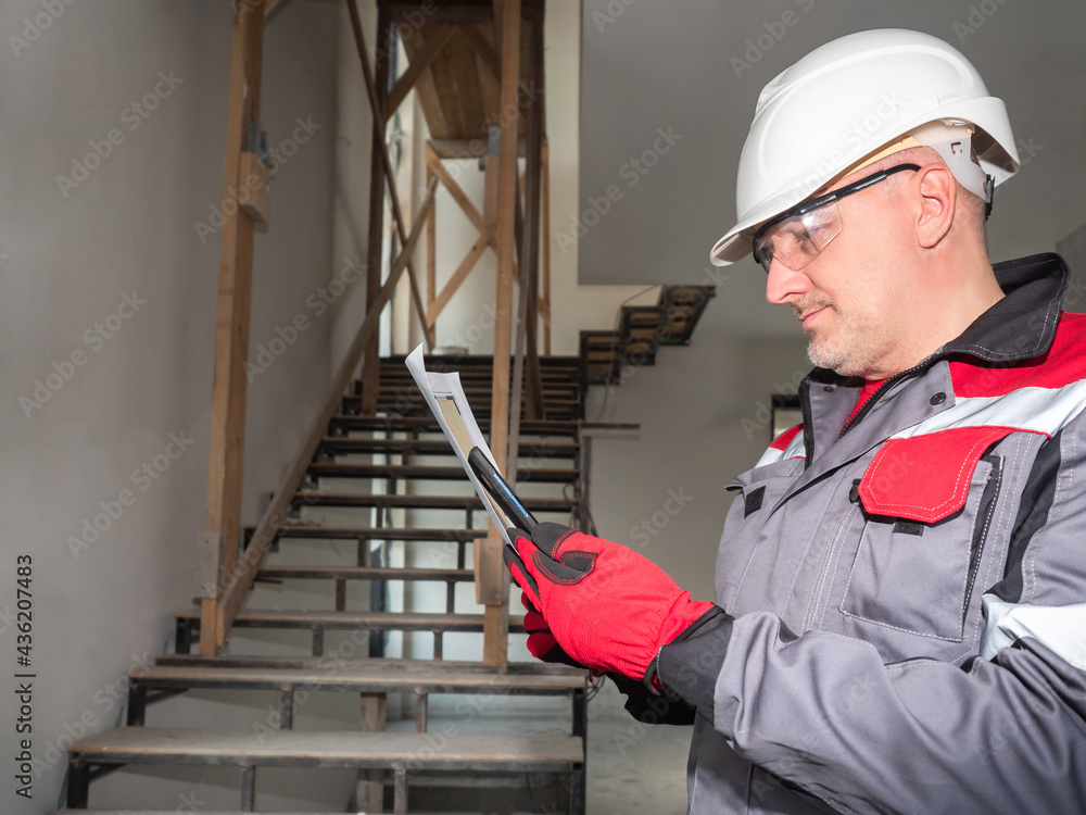 Poster engineer on a construction site. builder with a smartphone and drawings of premises in his hands. a 