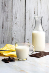 breakfast and snack with milk, chocolate and homemade breads with bottle and elegant glass and sugar on counter and wooden background
