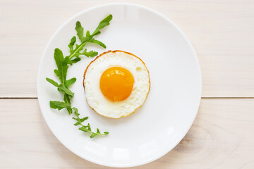 Fried eggs with arugula in a plate. Horizontal orientation, top view. 