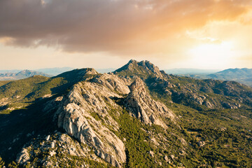 View from above, stunning aerial view of a valley surrounded by some granite mountains and green vegetation during a beautiful sunset. San Pantaleo, Sardinia, Italy.