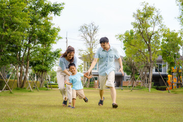 Asian family playing catch on yard or public park in neighborhood for daily health and well being,...