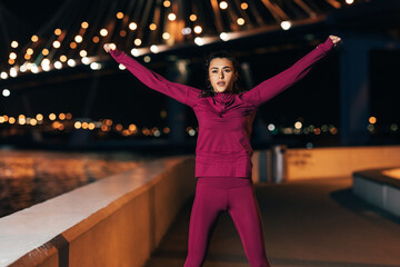 Young middle eastern woman in sports clothes doing warming up exercises outdoors