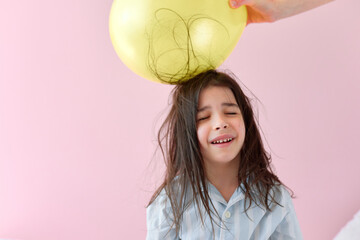 The cheerful little girl in pajama with electrified hair during the electrification balloon...
