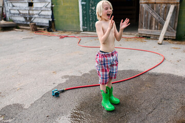 Canada, Ontario, Kingston, Shirtless boy playing with gardening hose