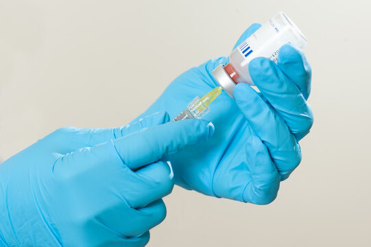hand in glove with gloves and filler vial
