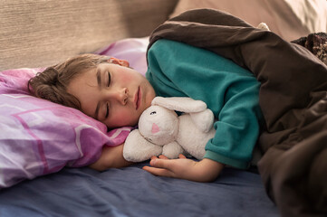 blond boy sleeping in bed holding a toy