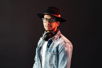 Young African American man portrait wearing headphones and hat and enjoy music over black Background