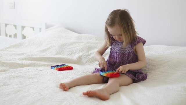 Adorable little girl playing with pop it fidget