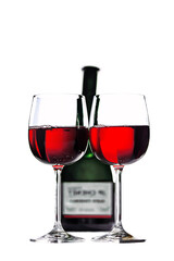 Two goblets of red wine in front of wine bottle. Isolated on white
