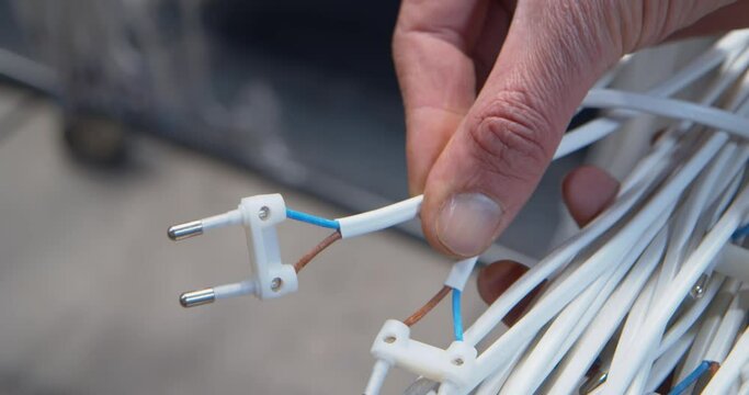 Operator examing the quality of a bunch of electric wires with a small plug