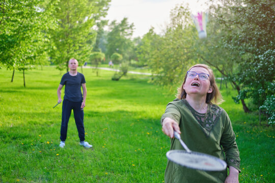 An Adult Woman Plays Badminton With Her Son On The Lawn In The Park