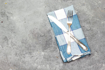 Fototapeta na wymiar Knife and fork above checkered white and blue napkin