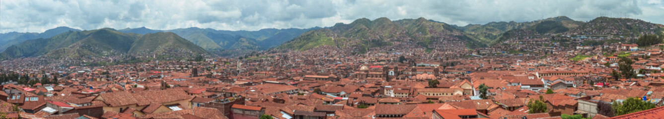 Fototapeta na wymiar Panoramic photo aerial of rooftops in Cusco city. Tile roofs in a valley surrounded by green. Peru, South America