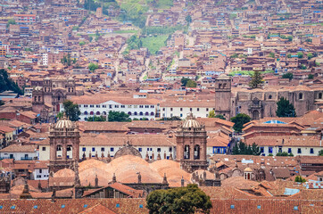 Fototapeta na wymiar Aerial view of rooftops in Cusco city. Houses and churches from a fair away point. Peru, South America