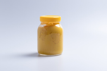 Yellow custard in glass bottle on a white background