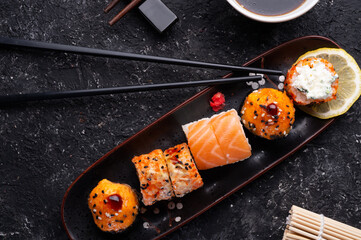sushi roll set served at black tray with black sticks at black  table. flat lay.
