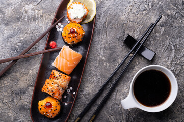 sushi roll set served at black tray at grey table. flat lay. close up