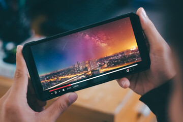 Online movie streaming with smartphone. Young man watching a movie on a mobile phone with an...