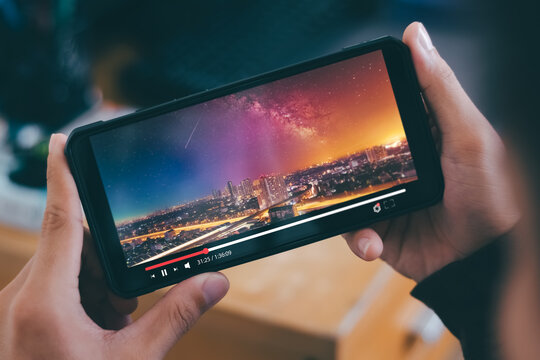 Online Movie Streaming With Smartphone. Young Man Watching A Movie On A Mobile Phone With An Imaginary Video Player Service.