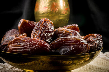 Big luxury dried date fruit in bowls on a linen napkin, kurma ramadan kareem concept, close up.