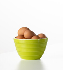 green bowl with brown eggs on white counter