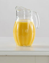 orange juice in jug on a white table 