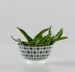 green chili peppers in a checker bowl on a white counter