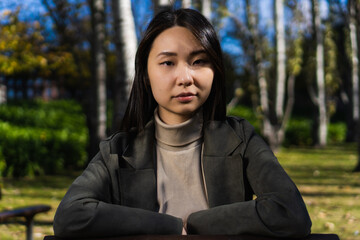 portrait of a young multiracial Asian American business woman looking at the camera in a park.