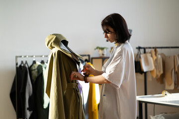 Young designer use needles to adjust collar details to model from new collection while working in...