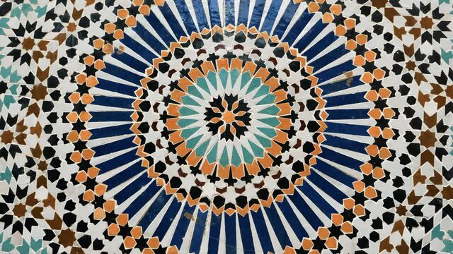 Colorful star-shaped pattern in traditional Islamic geometric design from a public fountain in Marrakech, Morocco. Made with natural colors from indigo, saffron, mint, kohl. Camera movement: rotating.