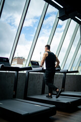 Handsome muscle man running in the gym. Young bodybuilder have cardio training.