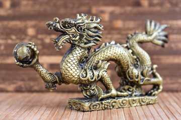 Bronze dragon on a wooden background. Statuette.
