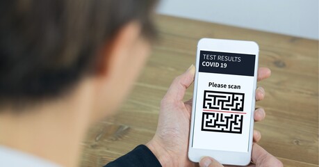 Composition of man holding smartphone with covid 19 test and qr code