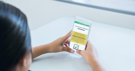 Composition of woman holding smartphone with covid 19 international certificate of vaccination
