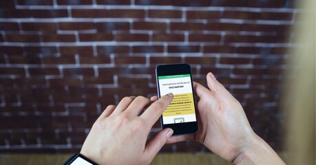 Composition of woman holding smartphone with covid 19 international certificate of vaccination
