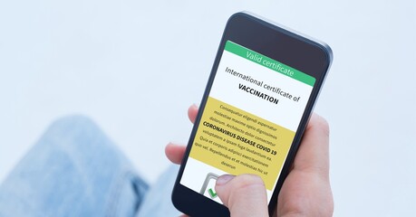 Composition of woman holding smartphone with covid 19 international certificate of vaccination