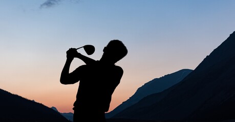 Composition of silhouette of male golf player over landscape and blue sky with copy space