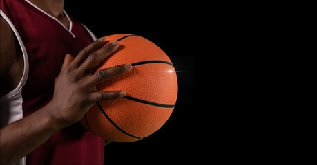 Composition of midsection of male basketball player with ball and copy space on black background