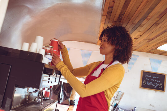 Mixed race woman preparing coffee by coffee machine in food truck