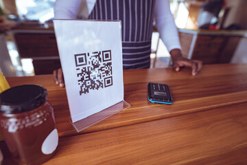 Midsection of african american man in food truck with qr code menu on worktop