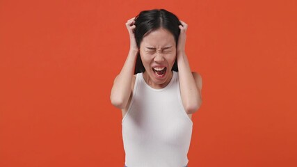 Crazy mad worry irritated sad angry brunette young asian woman 20s years old wears white tank top shirt closed eyes cover ears do not want to listen scream isolated on orange color background studio - Powered by Adobe