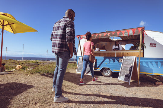 Smiling african american man in food truck waiting to take order from female customer