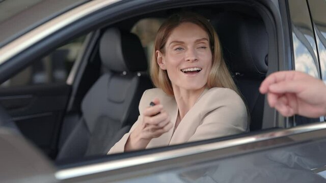 Happy woman taking car keys from male dealer