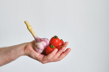 A man holds tomatoes and garlic in his hands. Healthy food, organic vegetables. Ripe fresh red...