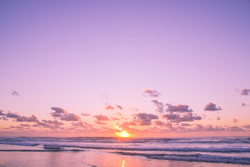 Purple sunset skies with small ocean waves at the beach