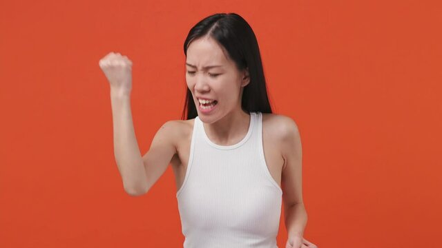 Smiling young asian woman 20s years old wears white tank top shirt countdown 1 2 3 one two three go celebrate win scream rejoices doing winner hands gesture isolated on orange color background studio