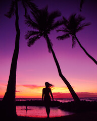 Fototapeta premium Woman walking towards the purple and pink sunset