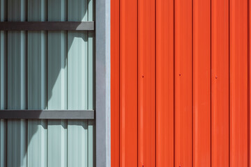 Sunlight and shadow on steel wall surface of storage room or garage with orange metal sheet fence wall outside of home, construction material concept