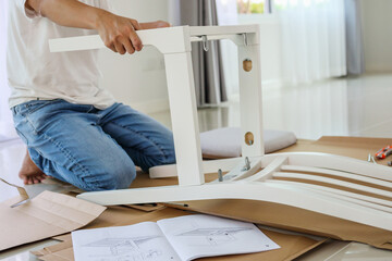 Man assembling white chair furniture at home